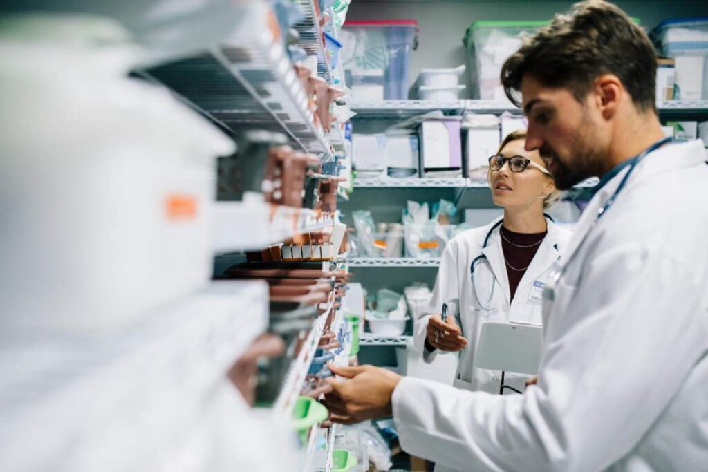 A person compares a labeled medicine bottle with colorful tablets on a clean table.