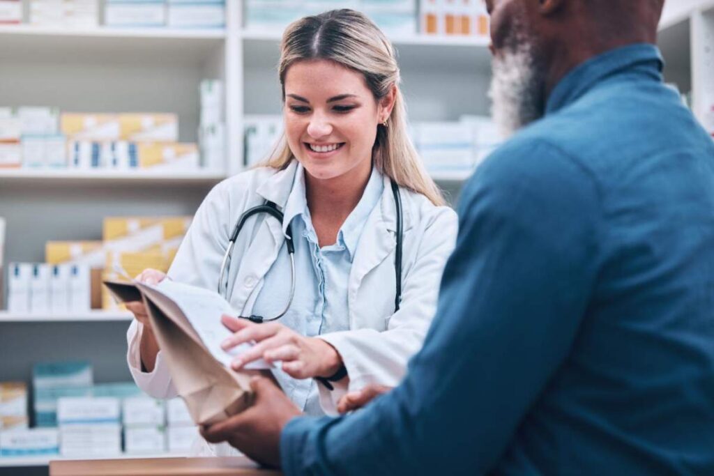 A patient and pharmacist review a prescription label and medication instructions at a pharmacy counter.