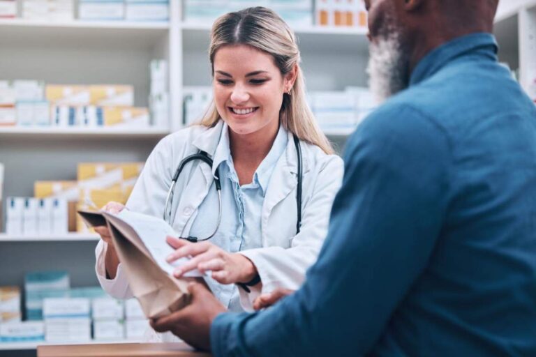 A patient and pharmacist review a prescription label and medication instructions at a pharmacy counter.